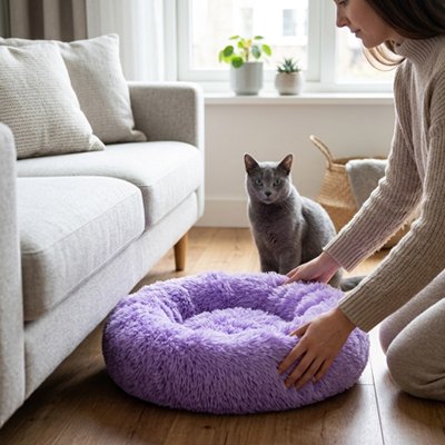 Une dame française entrain d'arranger un Coussin Chat Dorsalin™ violet à coté de son chat